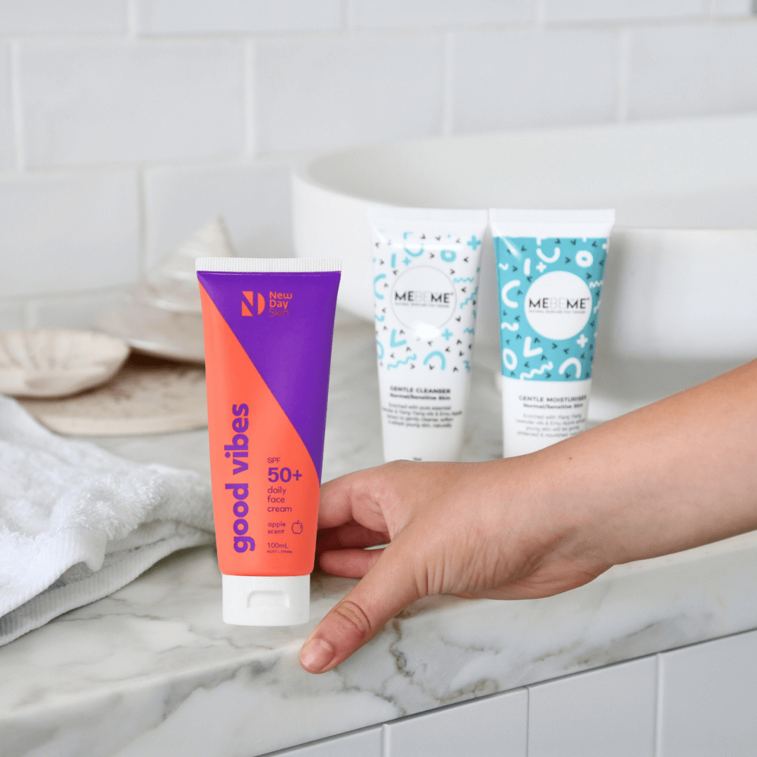 Gentle teen skin cleanser and moisturiser in the back ground a hand holding natural suncreen