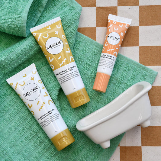 Three MEBEME skincare product tubes on a green towel with a small white bathtub toy.
