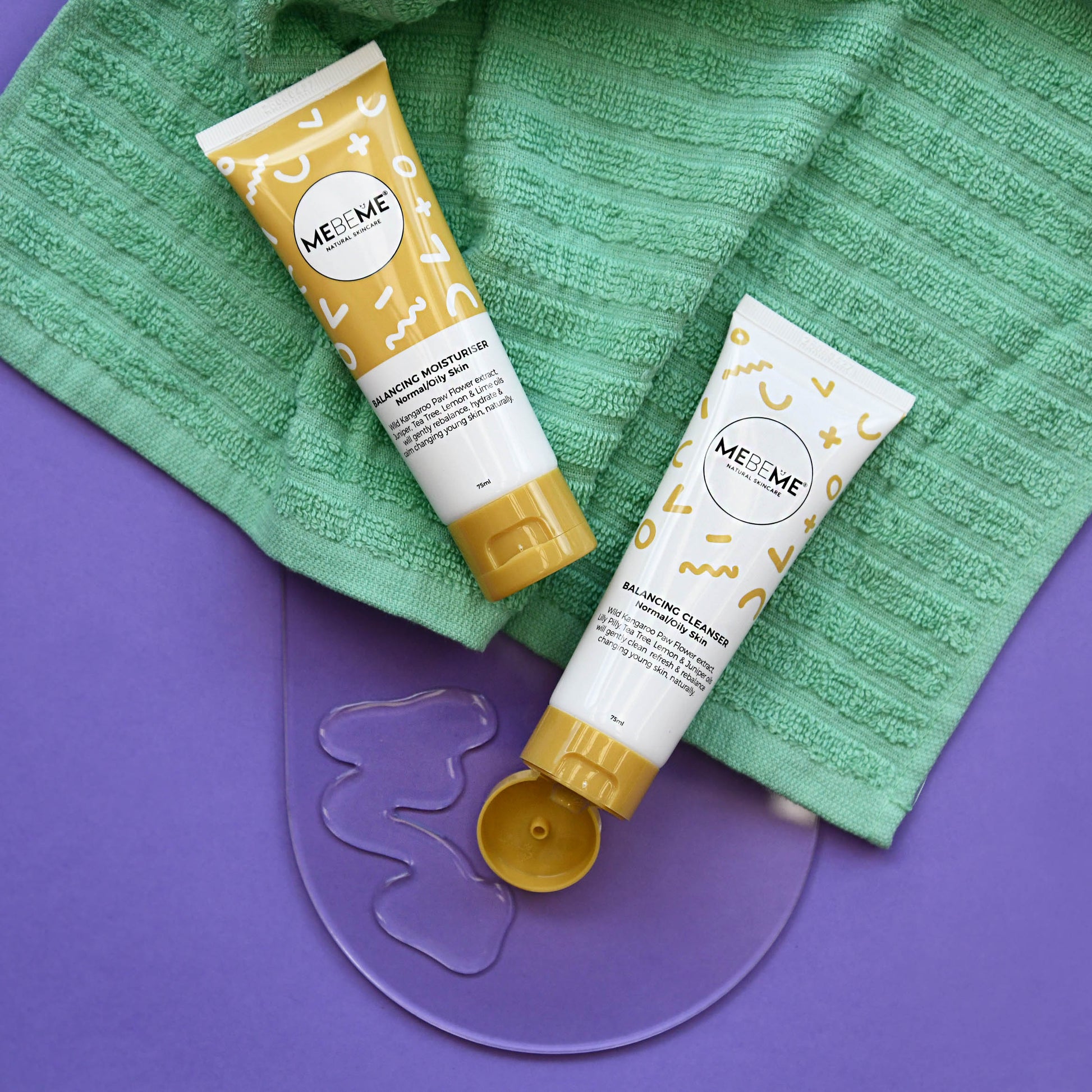 MEBEME balancing cleanser and balancing moisturiser tubes on a green towel with a purple background