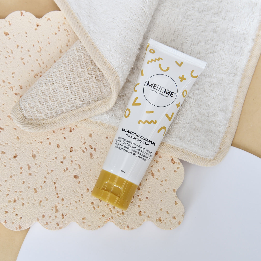 Tube of MEBEME Balancing Cleanser with a towel and washcloth on a neutral background