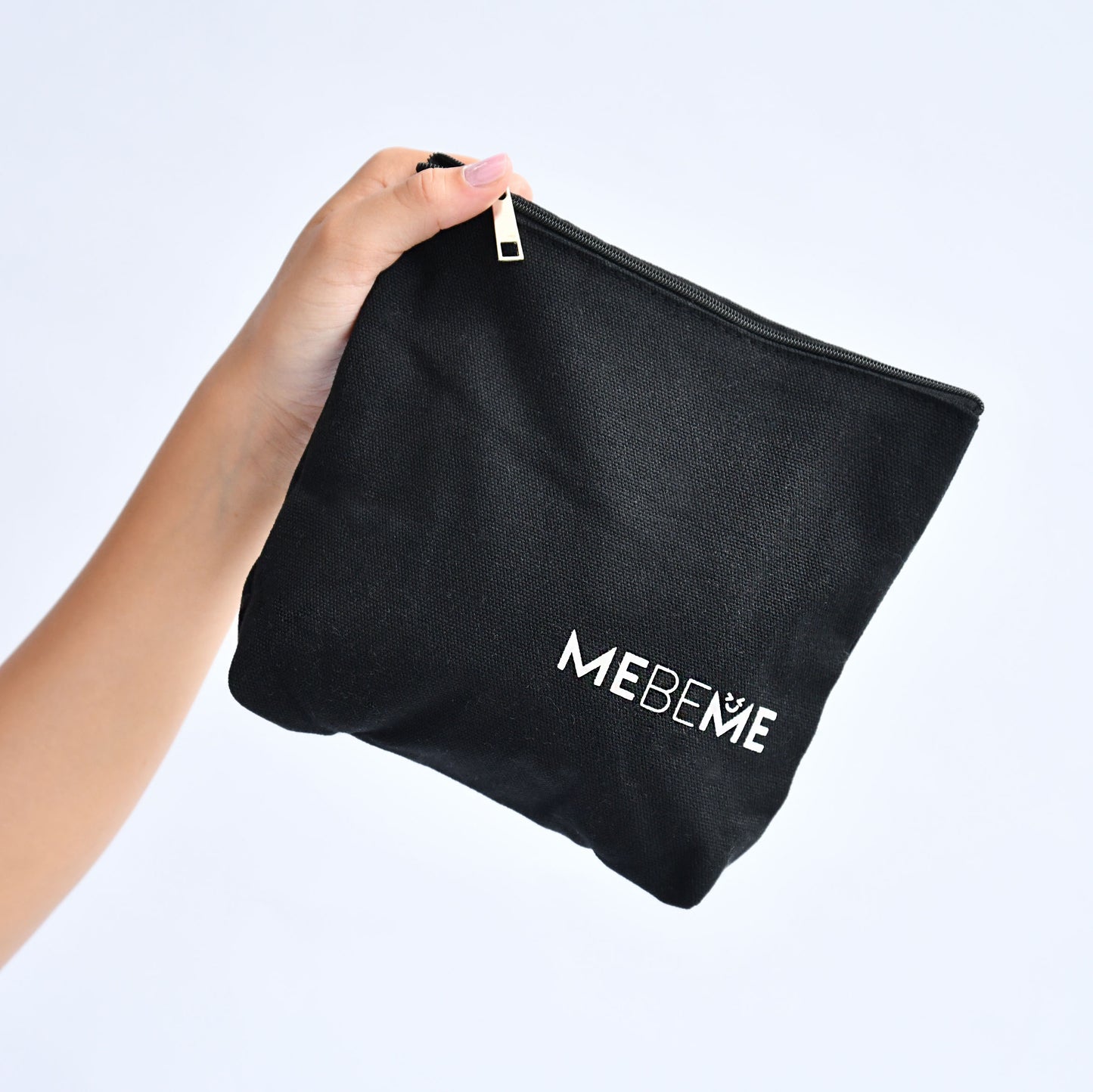 Black pouch with 'MEBEME' branding held by a hand against a light gray background