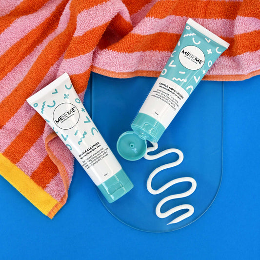 MEBEME gentle cleanser and gentle moisturiser on a blue surface with a colorful towel in the background