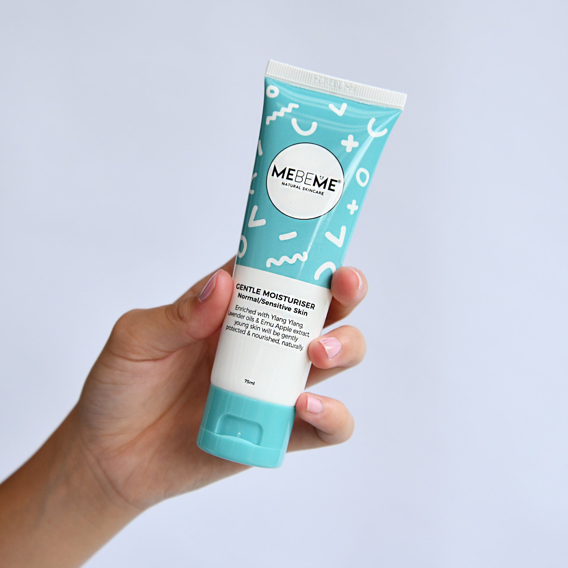 Hand holding a tube of MEBEME gentle moisturiser against a light gray background