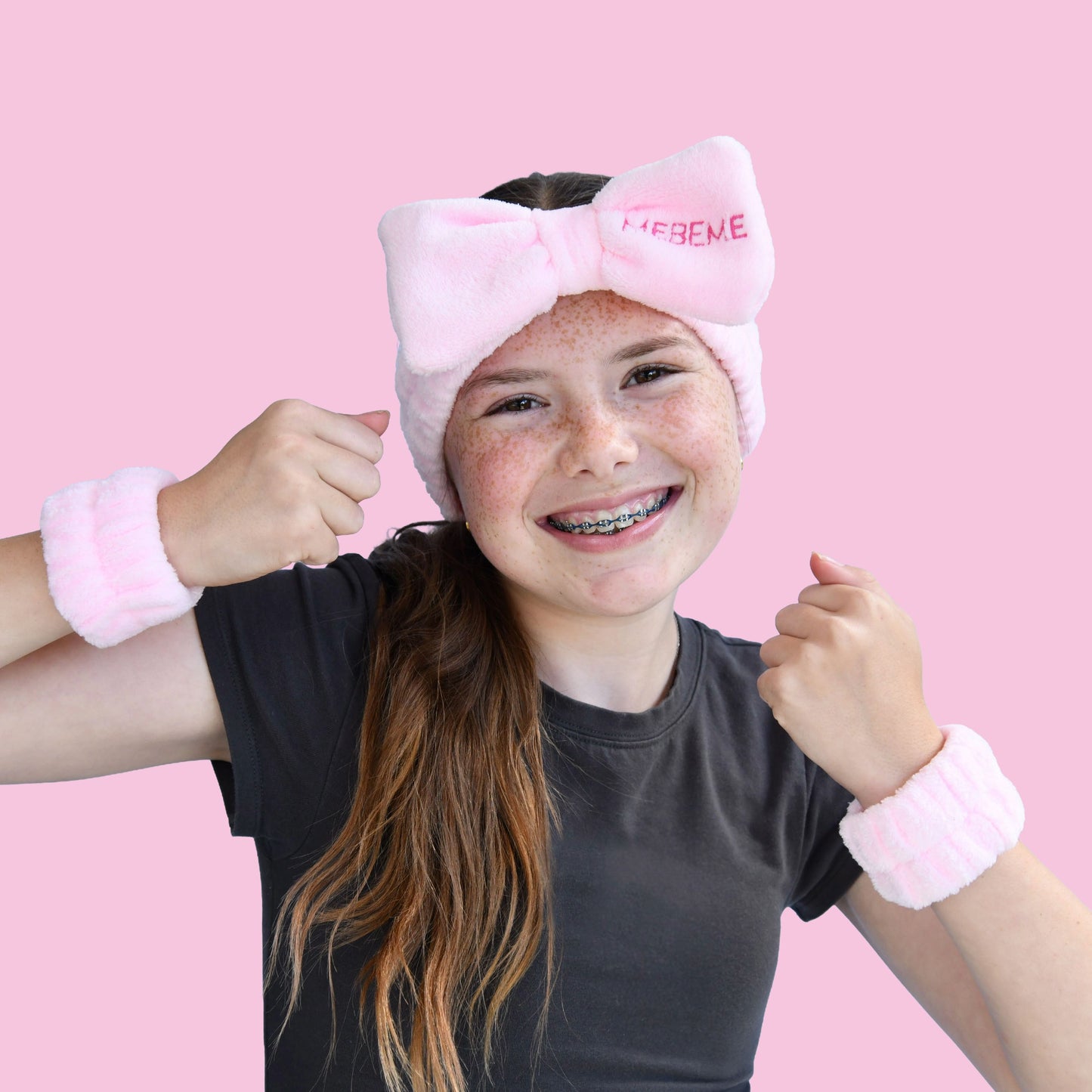 Girl wearing a pink headband with a bow and dry cuff set MEBEME branding, on a pink background