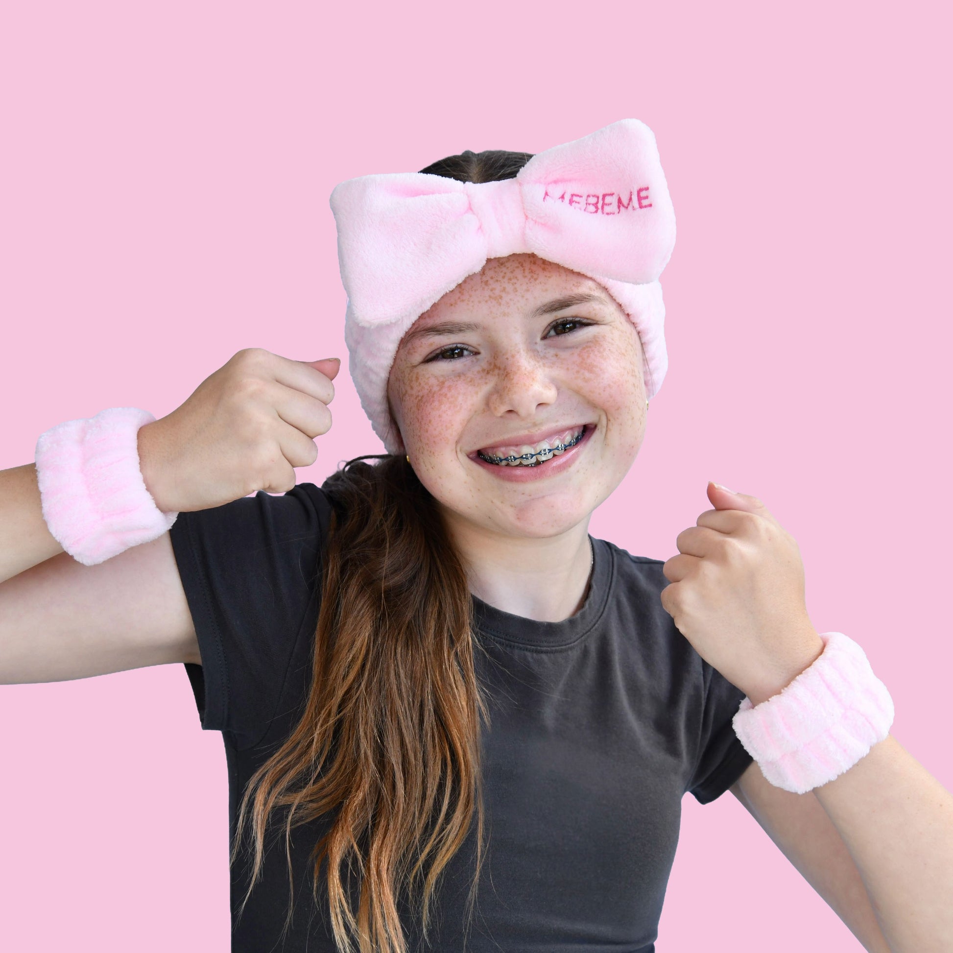 Girl wearing a pink headband with a bow and dry cuff set MEBEME branding, on a pink background