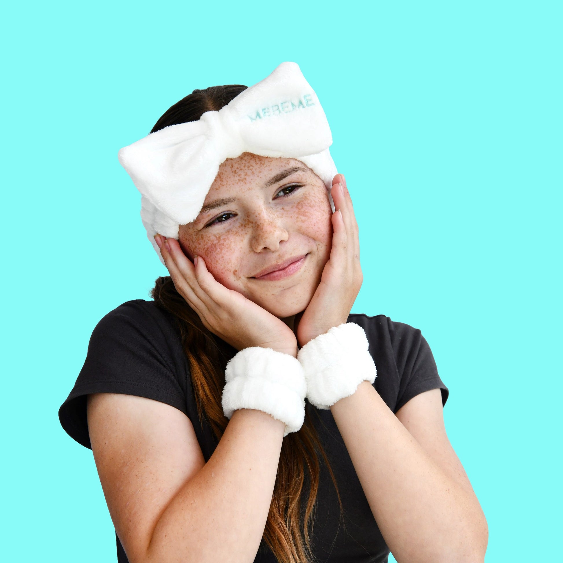 Person wearing a white fluffy headband and dry cuff set against a blue background