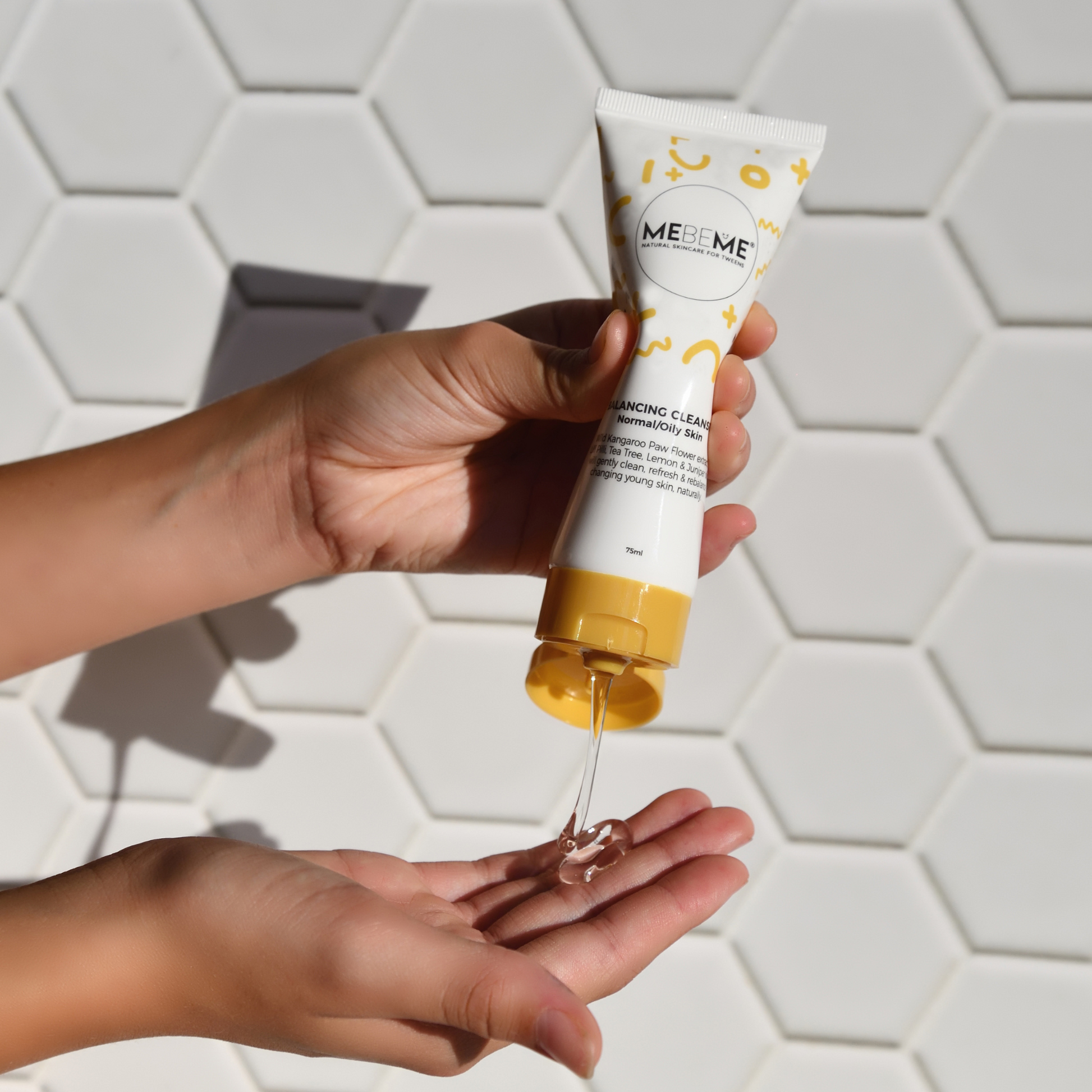 Person pouring MEME skincare product into their hand against a white tiled wall.