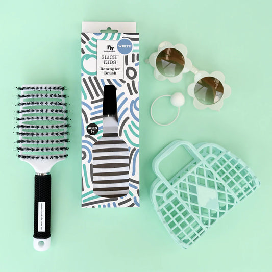 Detangler brush with packaging, sunglasses, and a green tool on a light green background