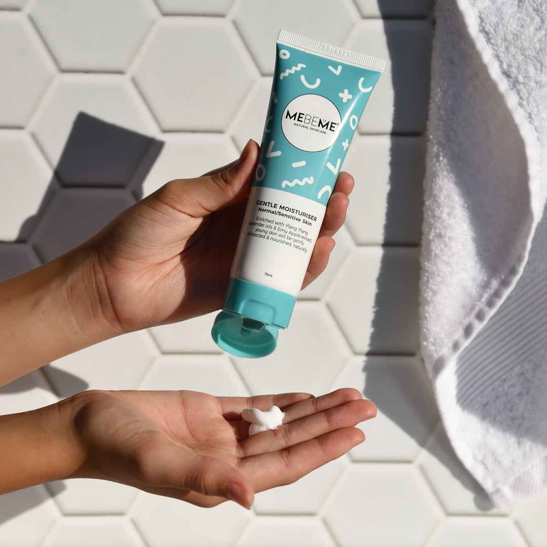 A person's hands holding a bottle of gentle moisturizer with some cream dispensed into the palm.
