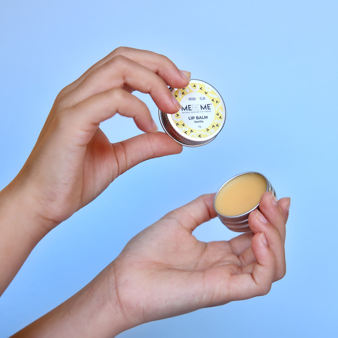 hands holding open vanilla lip balm tin